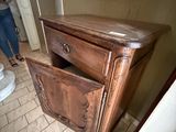 a woman taking a picture of a dresser in a bathroom