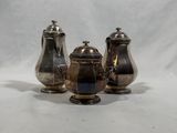 trois théières en métal argenté et un sucrier sur fond blanc