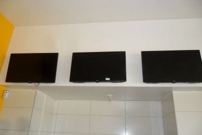 trois téléviseurs à écran plat fixés au mur au-dessus d'un lavabo