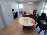 une pièce équipée d'une table, de chaises et d'un réfrigérateur