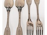 quatre fourchettes et cuillères sont alignées sur une surface blanche