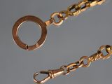a close up of a gold chain with a ring on it