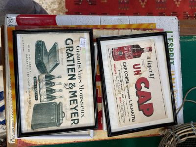 deux photos encadrées représentant d'anciennes publicités, posées sur une table