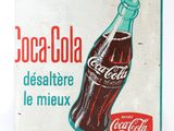 an old coca cola sign is displayed on a white surface
