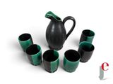 a black and green pitcher and six cups in a circle