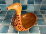 a wooden duck shaped bowl sitting on a tiled floor