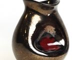 a black and red vase sitting on a white surface