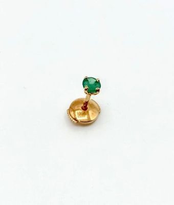 gros plan d'une bague en or avec une pierre verte