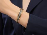 a woman wearing a black blazer and a gold bracelet