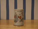 une petite tasse posée sur une table, avec en arrière-plan un mur rayé de bleu et de blanc