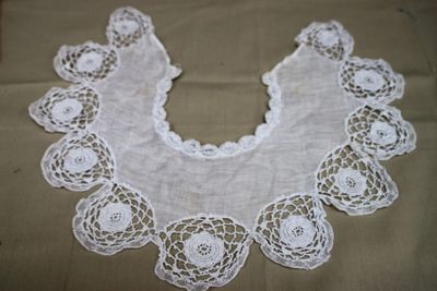 un col en dentelle blanche au crochet orné de fleurs, posé sur une table
