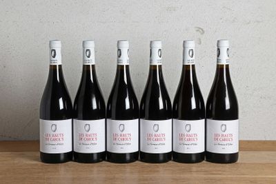 six bottles of red wine lined up on a wooden table