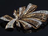 an image of a gold and diamond broochle on a black surface