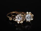 une paire de boucles d'oreilles en or et diamants sur une surface noire