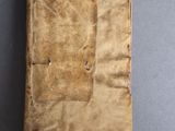 an old book sitting on top of a table covered in brown paper