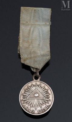 médaille d'argent sur laquelle est représenté un œil, posée sur un fond noir