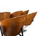 four wooden chairs sitting in a row on a white surface