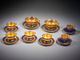 six tasses et soucoupes aux bords dorés sur fond gris