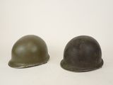 pair of army helmets on a white surface with a white background