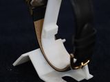 the watch is sitting on top of the stand on the black surface