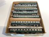 six green and white train cars in a cardboard box on a table