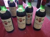 six bouteilles de vin sont alignées sur une nappe rouge