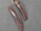 a close up of two brown snakeskin watch straps on a gray surface
