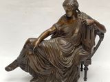 statue en bronze représentant une femme assise sur une chaise avec un chien