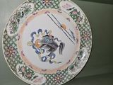a plate with a dragon on it sitting on a shelf
