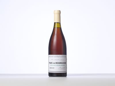 La bouteille de vin est posée sur une table devant un fond blanc.