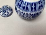 a blue and white bowl with a lid next to a small container