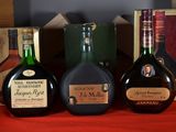 trois bouteilles d'alcool posées sur une table à côté d'une boîte de livres