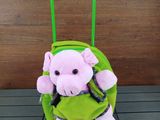 une peluche assise sur une valise verte