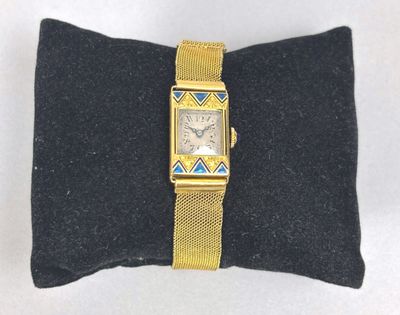 an image of a gold watch on a black pillow on a white surface