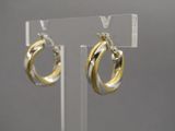 boucles d'oreilles créoles bicolores or et argent, présentées sur un support en acrylique transparent