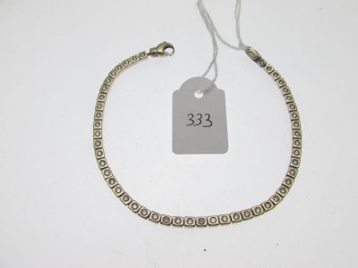 un bracelet en argent muni d'une plaque, posé sur une surface blanche