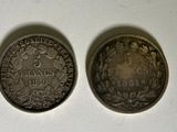 two silver coins sitting next to each other on a white surface