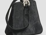 sac à main noir en daim avec un fermoir métallique sur fond blanc