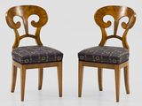 two wooden chairs with patterned upholstered seats on a white background