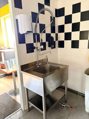 a sink in the corner of a kitchen with a black and white checkered wall