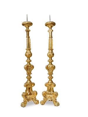 a pair of gold candlesticks on a white background