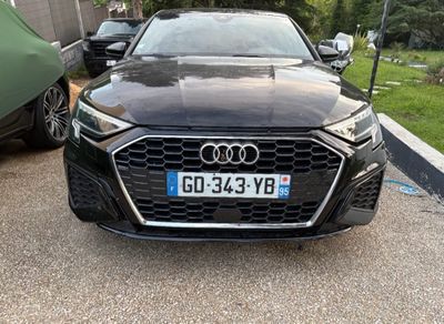 a black audi parked in a parking lot next to a car