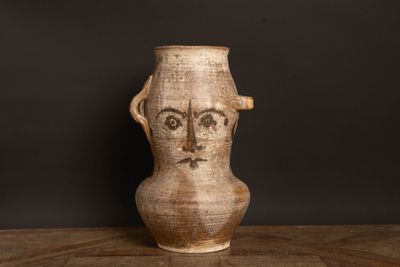 un vase marron orné d'un visage, posé sur une table