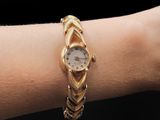 someone is wearing a gold bracelet with a watch on their wrist