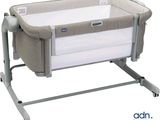 the baby crib is sitting on a metal stand with a white cover