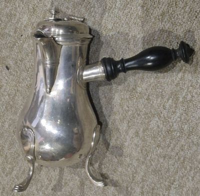 une cafetière en argent posée par terre à côté d'une poignée noire