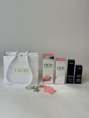 a white bag with a keychain, lipstick, and other items sitting on a table