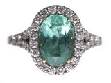 gros plan d'une bague avec une pierre verte entourée de diamants blancs