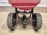 an image of a red spreader sitting on top of a cement floor