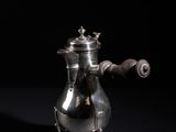 an antique silver coffee pot with a wooden handle on a black background